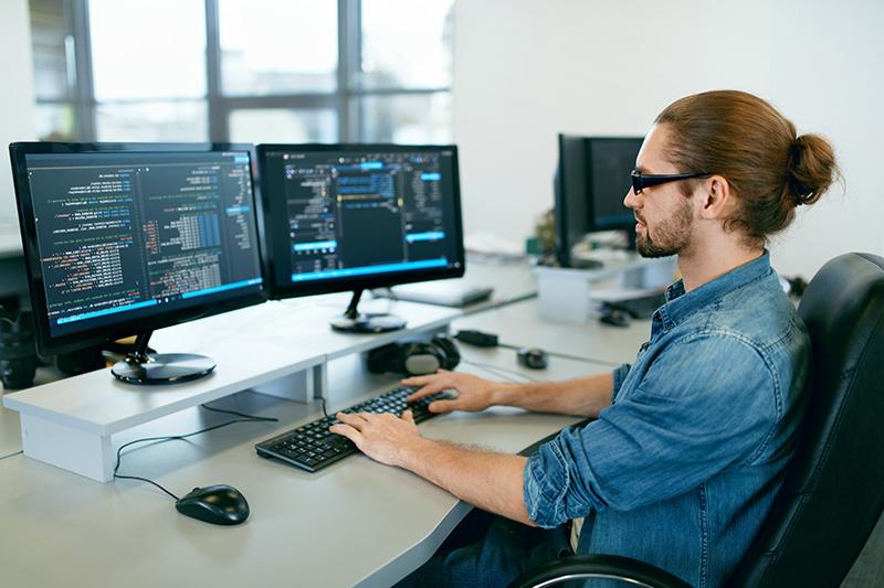 Programming. Man Working On Computer In IT Office, Sitting At Desk Writing Codes. 软件开发公司的程序员，在项目中输入数据代码. High Quality Image.